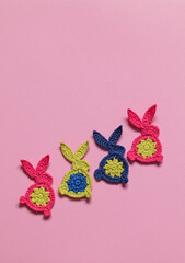Crochet Easter bunnies on a pink background. Handmade Easter decoration. Top view. Copy space.
