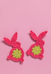 Two crochet pink yellow bunnies close up on a pink backgound. Happy Easter concept. Top view. Copy space.