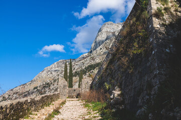 Kotor, Montenegro, process of climbing to the top of San Giovanni Fortress, Fort St. John, old medieval town, hiking on the Ladder of Kotor, sunny day with a blue sky and mount Lovcen and Orjen