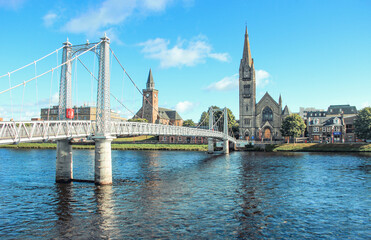 Fototapeta na wymiar Greig St Bridge across Ness River and the Free Church of Scotland on the river bank in sunny days