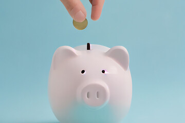 Eine Hand steckt eine M&uuml;nze zum sparen in ein Sparschwein mit blauen Hintergrund. Finanz- und Geldeinlagenkonzept - Generative Ai 