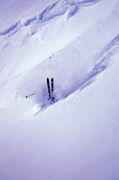 A skier falls while backcountry skiing in powder snow.