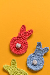 Funny crochet bunnies with white tails on a yellow background. Happy Esater concept. Top view. Copy space.