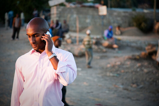 A young Ethiopian man talks on his cellular phone on a dusty street in Ethiopia.
