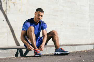 African American male athlete tying shoelaces