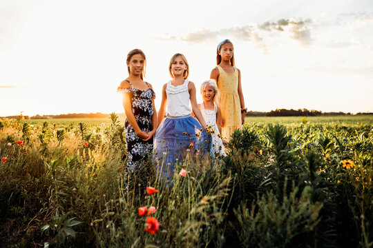young girls walking through a field of wildflowers in summer