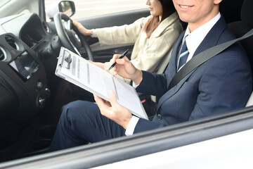 車の運転教習をする男性教官と女性生徒