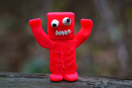 A figure of a red zombie made of plasticine is trying to scare. Funny monster.