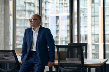 Fototapeta premium Elegant businessman chilling in office and looking to the side