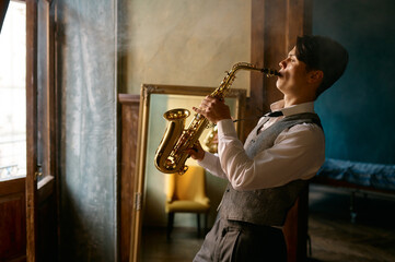 Fototapeta na wymiar Young elegant man playing gold alto saxophone in misty room