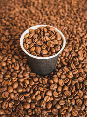 coffee beans in a paper cup on the background of coffee beans, epresso concept close up