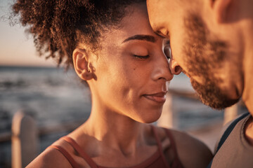 Black couple, hug and touching forehead embracing relationship, compassion or love and care by the beach. Happy man and woman with heads together smiling in happiness for support, trust or romance