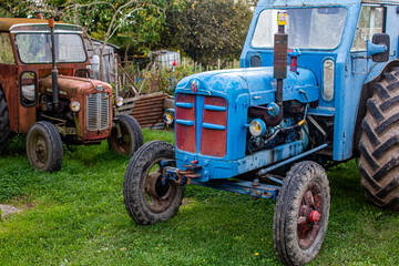 Obraz premium Two old rusty tractors in a backyard.