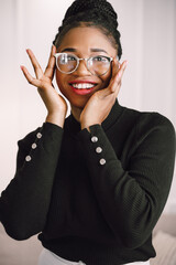 Cheerful woman standing with hands on her face and smiling