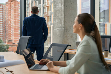 Stylish lady beholding her office admiring the window view