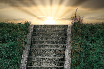 promienie słońca wschodzącego zza wzgórza ze schodami prowadzącymi w górę