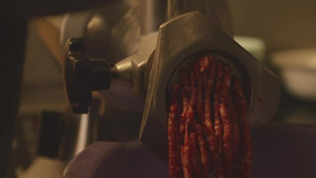 The process of grinding meat in an electric meat grinder.