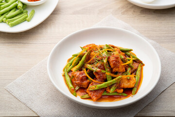 Stir fried sliced pork and red curry paste with sting bean in white plate,pad prik gaeng