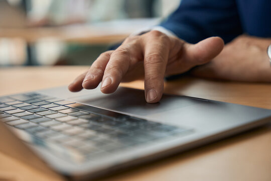 Male office worker using touchpad while working on laptop