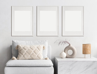 Blank picture frame mockup on white wall. Modern living room design. View of modern scandinavian style interior with sofa. Three vertical templates for artwork, painting, photo or poster