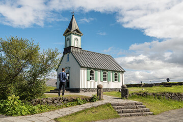Fototapeta na wymiar Caucasian tourist in front of Thingvallakirkja church in Iceland