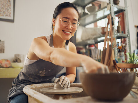 Happy, pottery or woman in designer workshop working on cup sculpture or mug mold in small business. Smile, artistic girl or creative Japanese worker busy with handicraft products as entrepreneur
