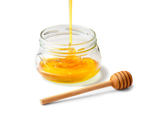 Honey is poured into an empty jar on a white background.