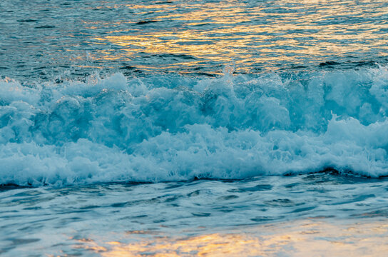 Sea waves texture with sunrise light reflection