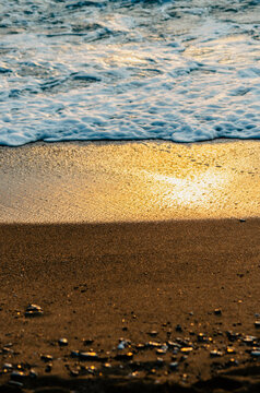Three layered texture on beach: sand, water and sunlight reflection