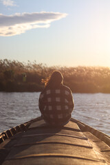 Mujer sentada en una barca observando el atardecer