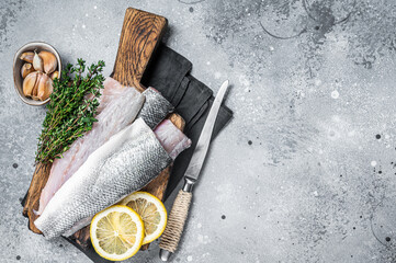 Fresh Raw Sea Bass fillets, Branzino fish with thyme and lemon. Gray background. Top view. Copy space