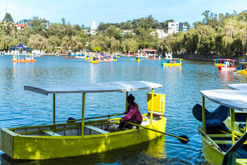 Baguio City, Philippines - Jan 2023: A woman steers a small wooden boat at a man-made lake in...