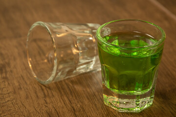 close up of shot glasses lined up on wooden bar background filled with green spirit cocktail and drunk at celebration for St Patrick's day 2023. Irish holiday popular drinking event when people party