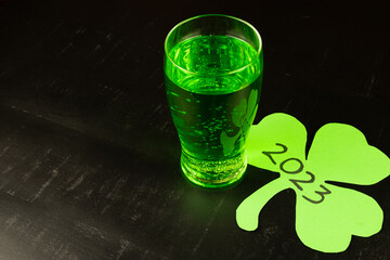 glass filled with green beer with 2023 shamrock on black background to be drunk at celebrations for...