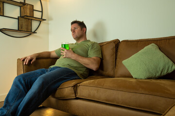 single lonely caucasian middle aged man spending St Patrick's day alone at home with green clothes...