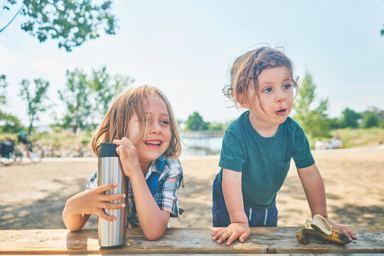 Two little boys sitting at picnic table in summer