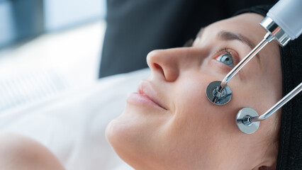 Naklejka premium Young caucasian woman on microcurrent therapy procedure. Beautician's office.
