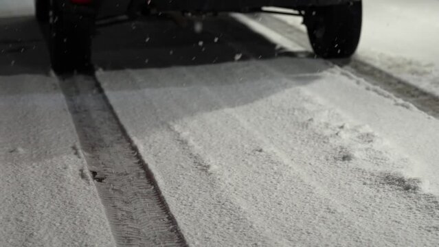 The tracks left by the winter tires of a car. 4k video during an evening snowfall. Winter tyre concept video.