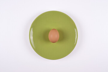 egg on plate, top view of raw egg on green plate on white background