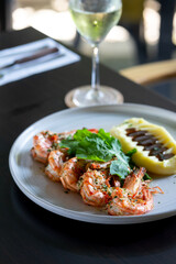 Grilled tiger prawns with mashed potatoes and herbs on the plate.