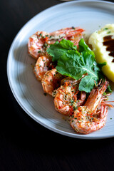 Grilled tiger prawns with mashed potatoes and herbs on the plate.