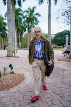 PHoto of a college professor walking on campus with blurry people in background