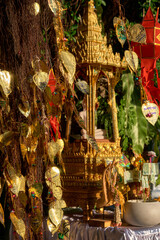 Thai Buddha altar, offerings, lanterns, golden leaves of Bodhi tree. 