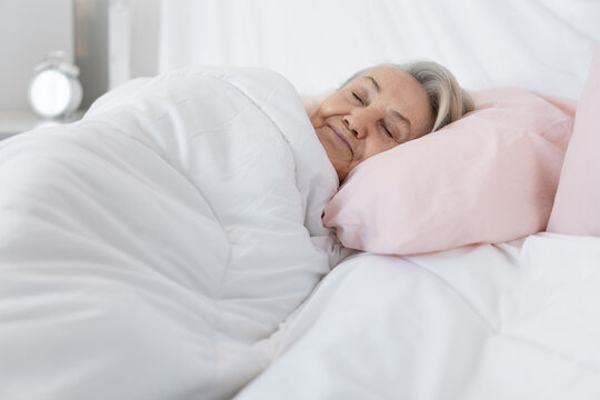 Older caucasian woman sleeping in bed at bedroom