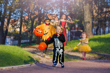Woman with kids run in Halloween costumes and scary pumpkin