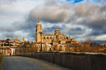 Fototapeta premium Stunning cityscape view of medieval Salamanca. View from ancient roman bridge. Famous Cathedral Nueva de Salamanca against cloudy sky. Pilgrimage place and touristic destination