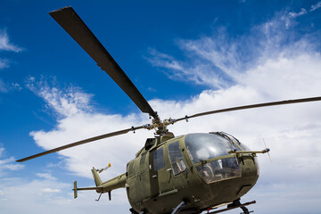 Fototapeta na wymiar Military helicopter over blue sky and white clouds