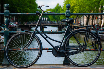 Fototapeta na wymiar A black bicycle over a canal in Amsterdam during the Summer