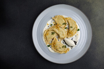 delicious Ukrainian dumplings with sauce on a plate.
