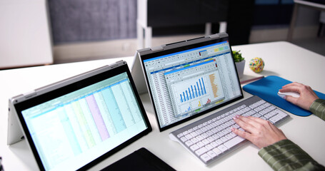 Businesswoman's Hand Examining Spreadsheet On Laptop
